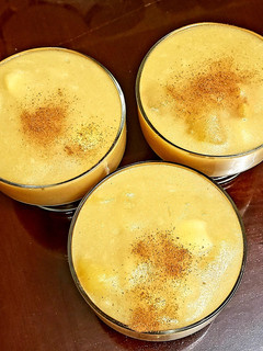 Champús in glass cups where you can see a thick, light yellow drink with small pieces of fruit that seem very refreshing. 